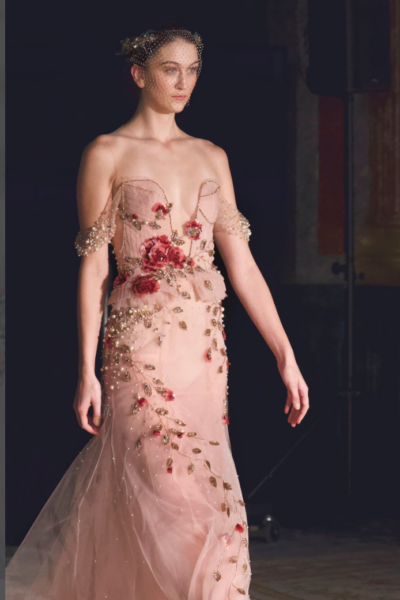 model wearing a pink off the shoulder gown with pearl and flower embellishments